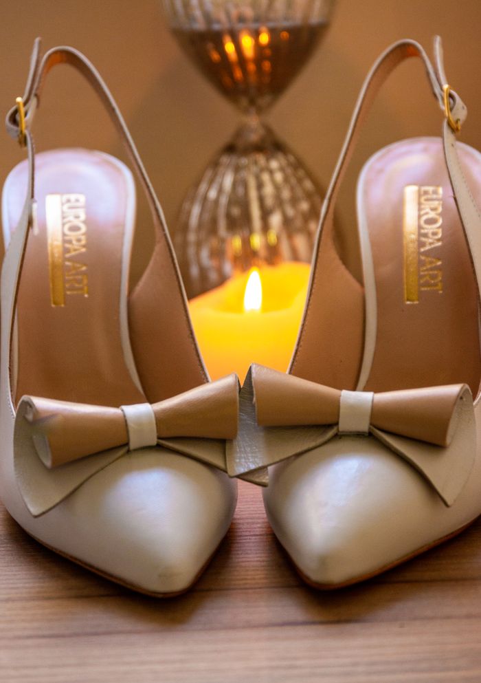 services-03 Close-up of elegant beige high heels with bows, set in warm, candlelit ambience for a stylish look.